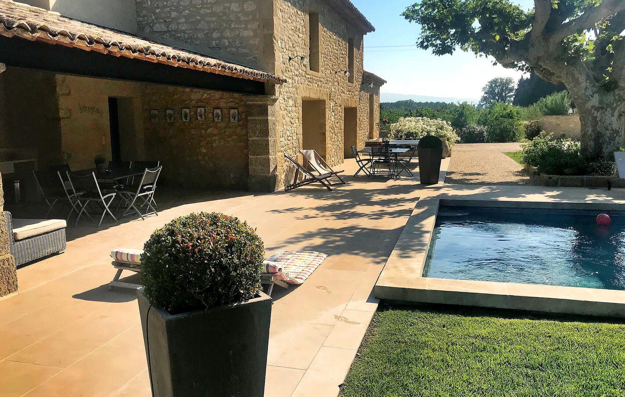 A pool area with a stone building, outdoor furniture, and a well-maintained lawn.