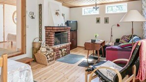 A cozy living room with a brick fireplace, wooden flooring, a sofa, and a television. - Awesome home in Linneryd with lake view (Linneryd)