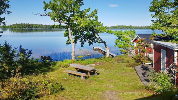 A lakeside cabin with a picnic table and a dock extending into the water. - Awesome home in Linneryd with lake view (Linneryd)