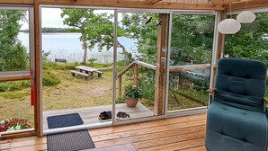 A wooden deck with a view of a lake, a bench, and a chair. - Awesome home in Linneryd with lake view (Linneryd)
