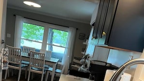 A kitchen with a large sink, a dining area with chairs, and a view through the window.