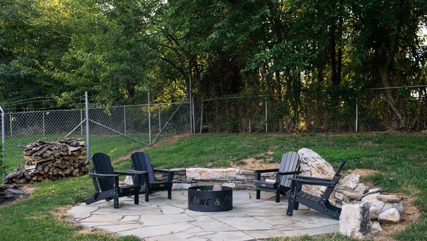 An outdoor seating area with Adirondack chairs and a stone fire pit. - The Mane & Co - No. 8 (Chambersburg)