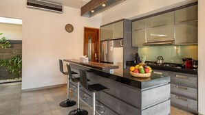 Una cuina moderna amb una illa central, electrodomèstics d'acer inoxidable i un plat de fruita.