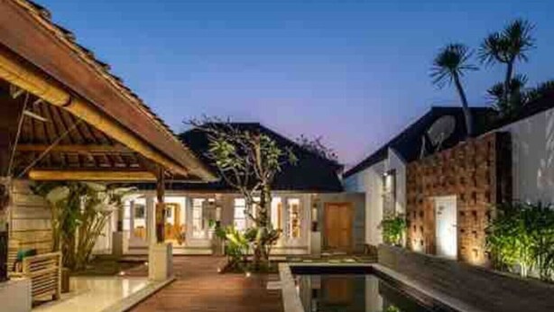 A modern villa with a wooden deck, a swimming pool, and a well-lit entrance. - 2 Bedroom Villa with private Pool in Seminyak Bali (Seminyak)