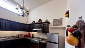 Eine Küche mit dunklen Holzausführungen, einem Edelstahl-Kühlschrank, einem Gasherd und einem Fliesenboden.