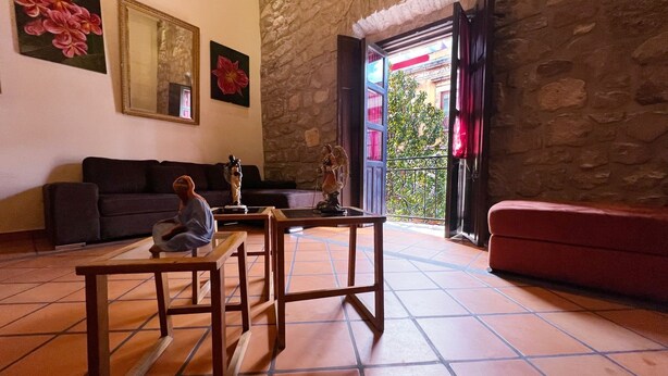 Ein gemütliches Wohnzimmer mit Steinwand, einer Couch, einem Couchtisch und einem Balkon mit Aussicht.