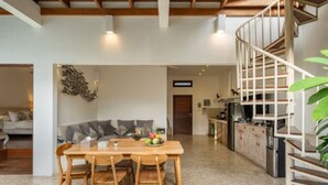 Eine moderne Küche mit Holztisch und -stühlen, einem Einbauofen und einer Wendeltreppe.