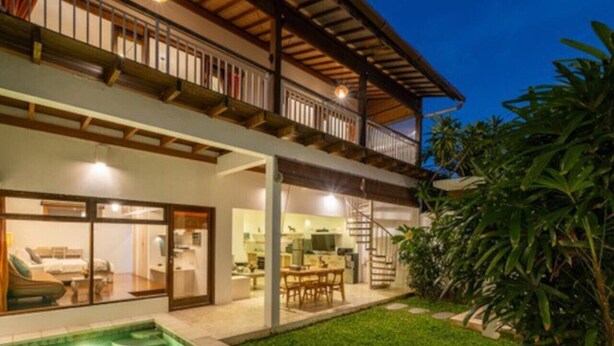 Ein zweistöckiges Haus mit Swimmingpool, Balkon und einem gepflegten Garten.