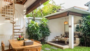A wooden dining table with chairs, a staircase, and a covered outdoor seating area with cushions. - 3 Bedroom cozy private pool Villa in Seminyak WIFI (Seminyak)