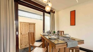 A dining area with a wooden table, chairs, and a glass-top table. There is a mirror on the wall and a window with curtains. - 2 Bedroom private Pool Seminyak (seminyak)