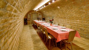 A long dining table with checkered tablecloths, wooden chairs, and a brick wall on one side. - Gorgeous home in Karanac with sauna (Karanac)