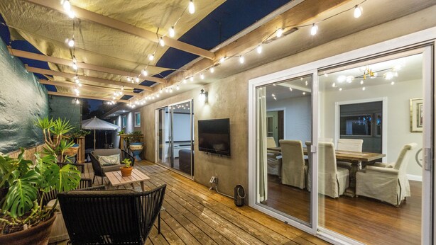 An outdoor patio with wooden flooring, potted plants, and string lights. - San Diego City Escape – Perfect for Families, Groups, & Business Travelers (San Diego)