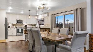 A modern kitchen with white cabinets, stainless steel appliances, and a dining area with a large table and chairs. - San Diego City Escape – Perfect for Families, Groups, & Business Travelers (San Diego)