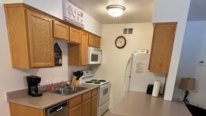 A compact kitchen with wooden cabinets, a microwave, a stove, and a refrigerator.