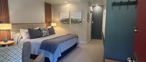 A modern bedroom with a bed, bedside tables, and a door.
