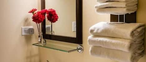 Un baño con un lavabo blanco, un espejo con tres luces, un perchero con toallas dobladas y un inodoro con un caja de pañuelos.