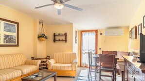 Una sala de estar con sofá, sillones, una mesa de centro y un comedor con sillas y una mesa.