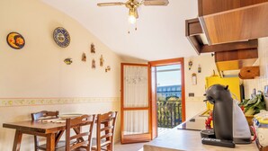 Cocina con armarios de madera, una mesa de comedor con sillas, un ventilador de techo y vistas al balcón exterior.