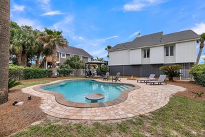 A swimming pool with a curved edge, surrounded by a brick patio and palm trees. - Stella Maris-Beautiful Deluxe Home w/ Private Pool & Ocean Views;Across from Beach Access (Edisto Beach)