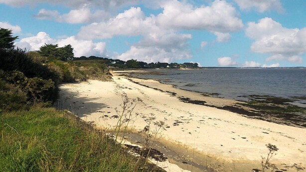 En sandstrand med en klar himmel och några få moln här och var.