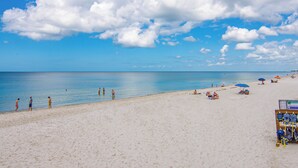 Una playa con gente, sombrillas y una caseta de salvavidas.