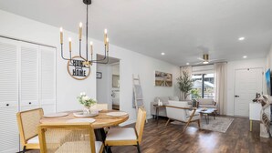 Una sala moderna con una mesa de comedor de madera, sillas de mimbre, una araña y un sofá.