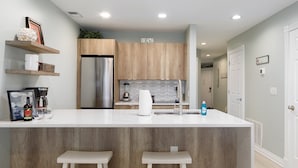 Une cuisine moderne dotée d’un îlot central, de meubles en bois et d’un réfrigérateur encastré.