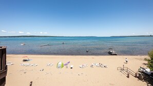 Une plage avec une eau d’un bleu limpide, plusieurs bateaux et des chaises de plage.