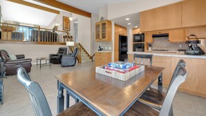 Amplia sala de estar con una mesa de comedor de madera, asientos cómodos y una cocina con armarios de madera y electrodomésticos modernos.