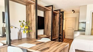 Un dormitorio moderno con un escritorio de madera, una silla, una cama y un televisor.