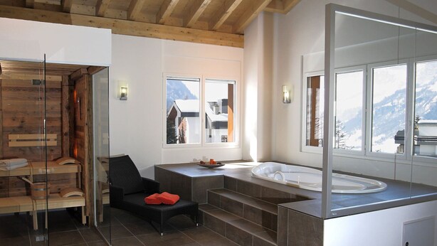 Un baño moderno con techo de madera, un espejo grande, una bañera y vistas a las montañas.