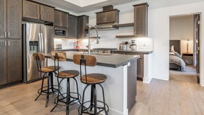 A modern kitchen with dark wood cabinets, stainless steel appliances, and a central island with bar stools.
