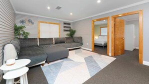 Uma sala de estar moderna com um sofá modular, uma mesinha e um tapete. Existem duas portas que dão para outros cômodos.