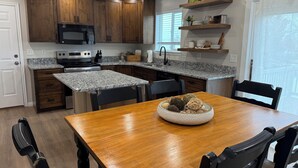 Una cocina moderna con armarios de madera, encimeras de granito y un comedor con mesa y sillas de madera.