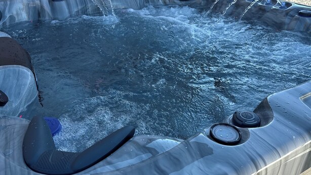 Un jacuzzi con múltiples chorros, un panel de control y una terraza de madera.