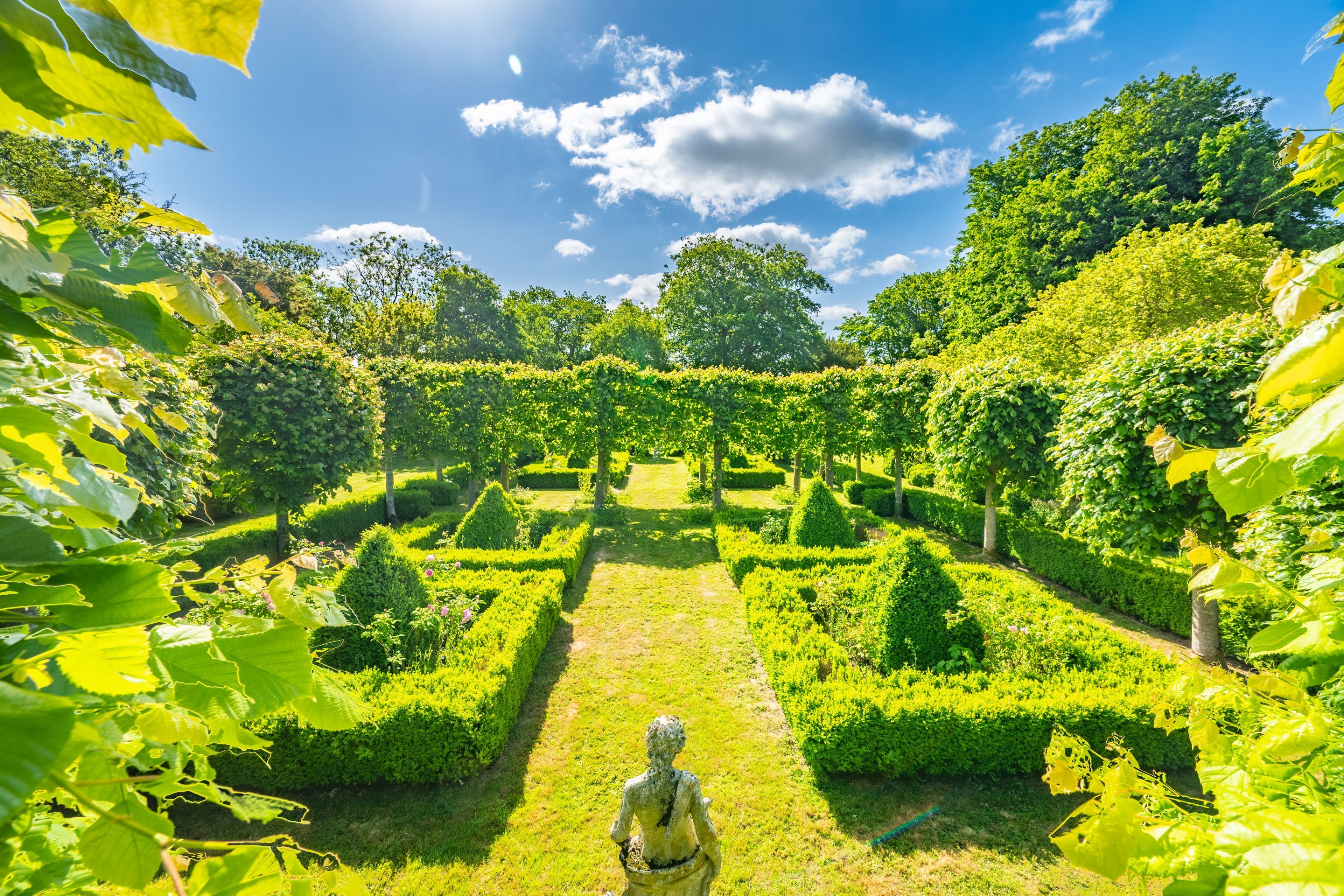 A well-maintained garden with a central pathway leading to a statue.