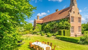 A large brick building with a garden and a dining area with tables and chairs. - Splendid 1,000 year old Medieval manor house  sleeps up to 14 or 22- Flemings Hall (Ipswich)
