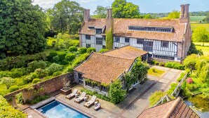 A large house with a swimming pool, surrounded by lush greenery and a well-maintained garden. - Splendid 1,000 year old Medieval manor house  sleeps up to 14 or 22- Flemings Hall (Ipswich)
