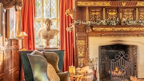 A luxurious room with a fireplace, a leather armchair, a chessboard, and a statue. - Splendid 1,000 year old Medieval manor house  sleeps up to 14 or 22- Flemings Hall (Ipswich)