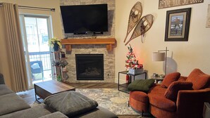 Una sala de estar con chimenea, un televisor de pantalla plana y un árbol de Navidad.
