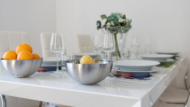 A dining table with a bowl of oranges, a bowl with a lemon, and a vase with flowers. - GuestHost - This cozy and bright 124 sqm penthouse apartment can accommodate up to 6 people and is located on the 6th floor of a 1970s building with lift.The apartment boasts a splendid view over the city of Pisa, which guests can admire from one of its  (Pisa)