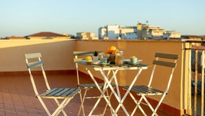 A rooftop terrace with a table set for two, chairs, and a view of the cityscape. - GuestHost - This cozy and bright 124 sqm penthouse apartment can accommodate up to 6 people and is located on the 6th floor of a 1970s building with lift.The apartment boasts a splendid view over the city of Pisa, which guests can admire from one of its  (Pisa)