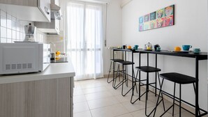 A modern kitchen with a white countertop, a built-in microwave, and a bar area with stools. - GuestHost - This cozy and bright 124 sqm penthouse apartment can accommodate up to 6 people and is located on the 6th floor of a 1970s building with lift.The apartment boasts a splendid view over the city of Pisa, which guests can admire from one of its  (Pisa)