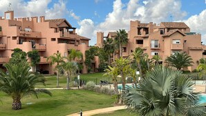 A resort with multiple buildings, a swimming pool, and well-maintained lawns with palm trees.