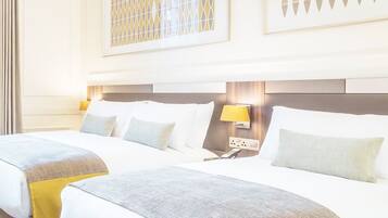 Habitación de hotel con dos camas, cabecera con lámpara y panel decorativo en la pared.