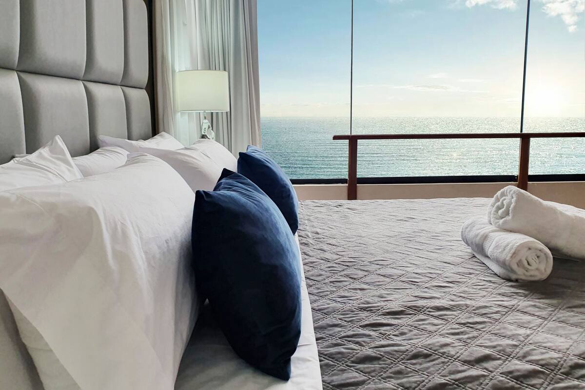 Une chambre d’hôtel avec un grand lit, une vue sur l’océan et un balcon.