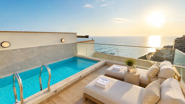 Una piscina en la azotea con vistas al océano y al paisaje urbano.