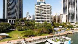 A waterfront hotel with a boat dock, surrounded by high-rise buildings and greenery.