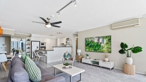 A modern living room with a grey sofa, coffee table, and a large TV screen.