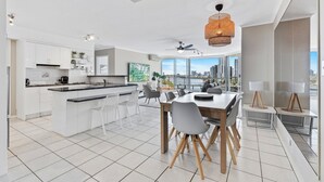 A modern kitchen with white cabinets, a central island, and a dining area with a large table and chairs.